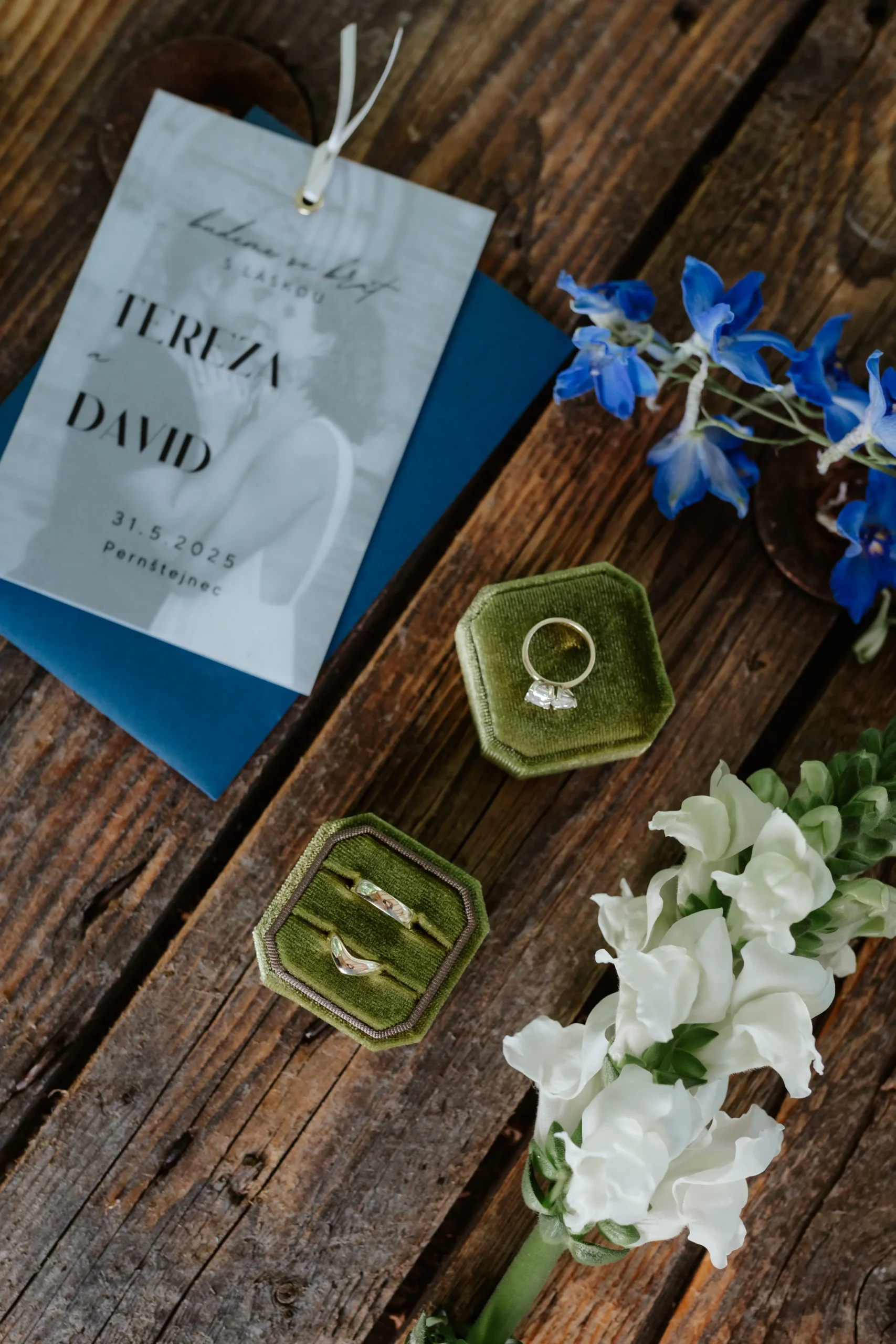 Svatební flatlay se svatební pozvánkou, snubními prsteny a svatební květinou.